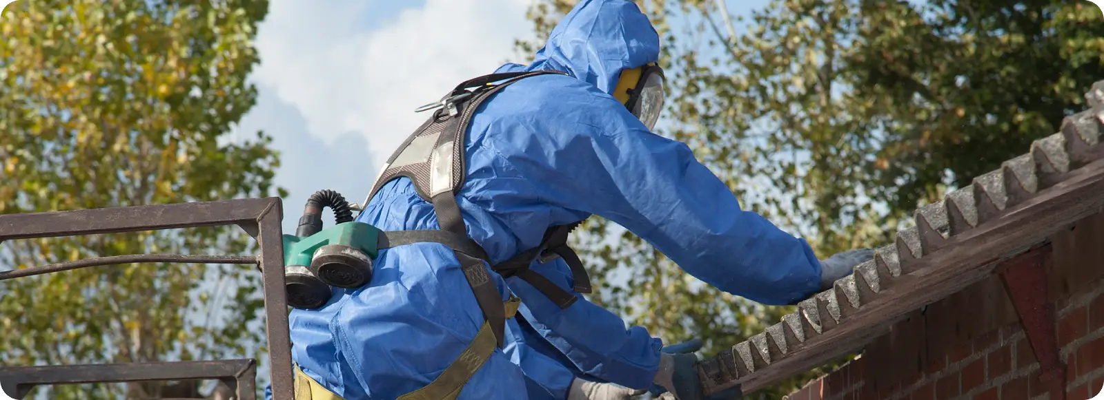 A Worker in protective gear conducting asbestos testing on a roof.