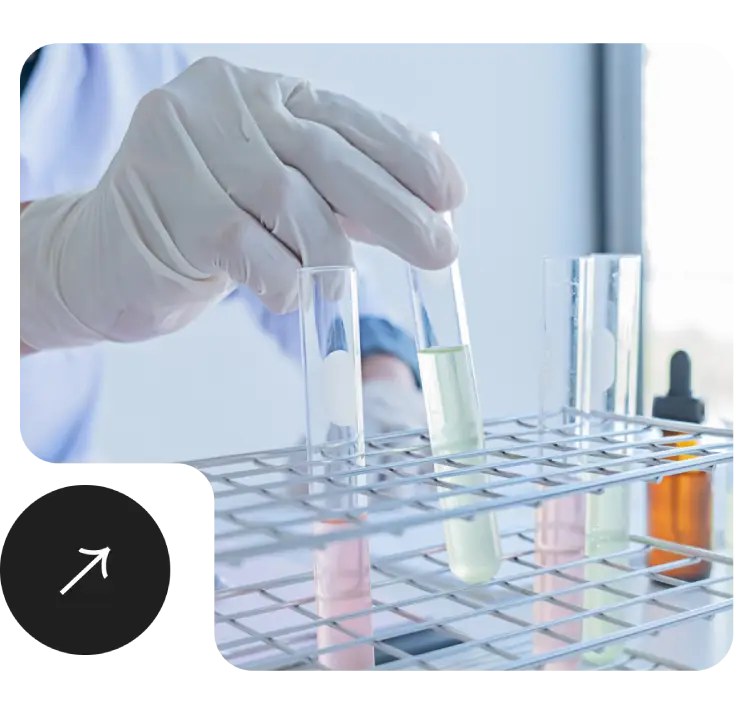 A person in a lab coat holds a test tube for water testing.