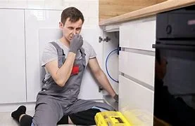Technician reacting to bad odor under sink investigating plumbing issues to get rid of mold smell in kitchen.
