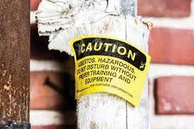 Warning label on asbestos-insulated pipe highlighting the importance of following asbestos requirements for safety