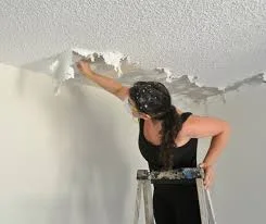 Woman scraping popcorn ceiling, risking exposure to asbestos in popcorn ceiling without proper protection.