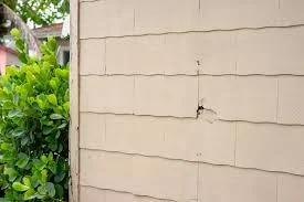 Cracked fiber cement siding on a home exterior, illustrating what does asbestos look like in exterior building materials
