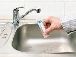 Water sample being collected from kitchen sink for home environmental testing