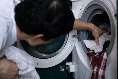 Checking clothes for mold in washing machine during laundry routine