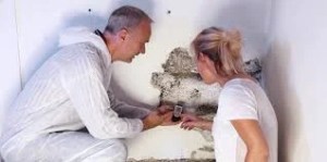 Inspector checking wall mold damage and discussing can you stay in home during mold remediation