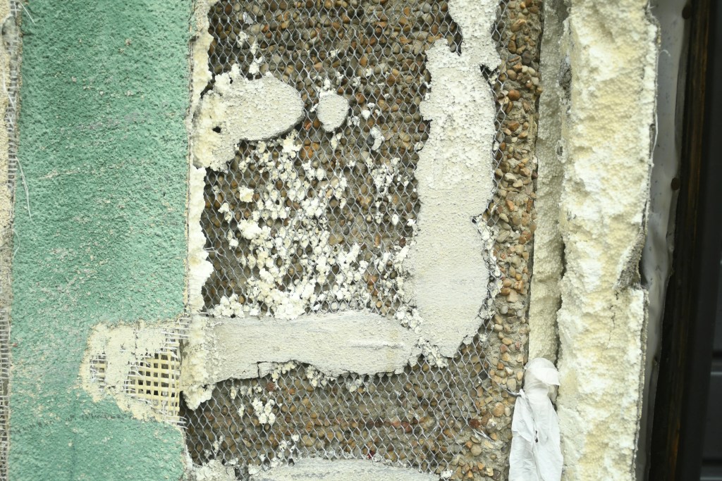 How to tell the difference between asbestos and fibre cement in damaged wall material with exposed mesh backing.